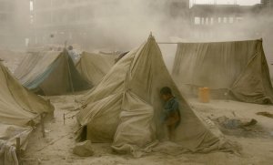 Афганский ребенок скрывается от шторма позади палатки в лагере беженцев в Кабуле. 7 октября 2008 год. MANPREET ROMANA/AFP/Getty Images